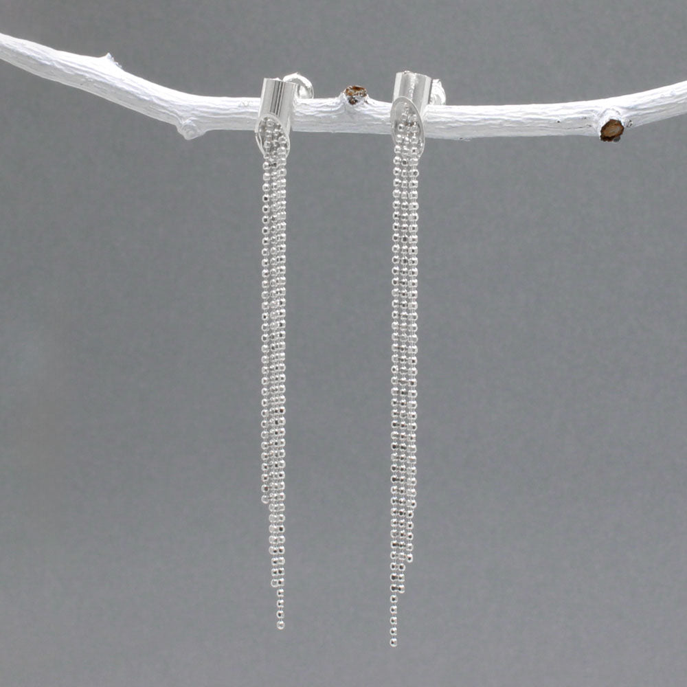 Áine - Cylinder with Chains Silver Earrings - Stud Design: Four chains of different lengths cascading from the center of the cylinder Cylinder Diameter: 4 MM Total Length: 61 MM from top to bottom Material: Sterling silver with a highly polished finish Fastening: Sterling silver friction post