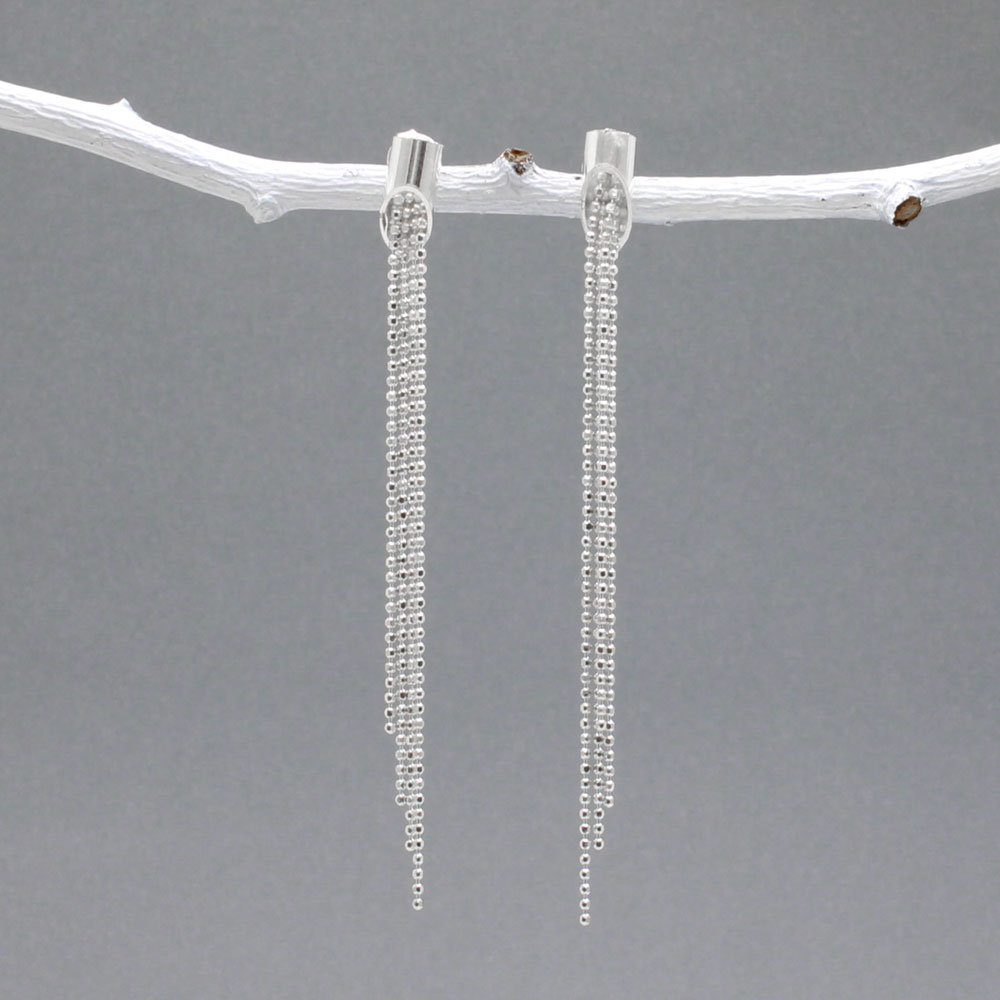 Áine - Cylinder with Chains Silver Earrings - Stud Design: Four chains of different lengths cascading from the center of the cylinder Cylinder Diameter: 4 MM Total Length: 61 MM from top to bottom Material: Sterling silver with a highly polished finish Fastening: Sterling silver friction post
