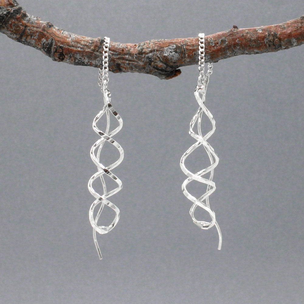 The Áine Small Helix Silver Threader Earrings bring a playful and elegant twist to your jewellery collection. These handcrafted earrings feature a slender helix shape with a lightly hammered finish, suspended from a fine silver chain that threads through the ear and connects to a polished post. The movement and shape give them a graceful, contemporary edge.
