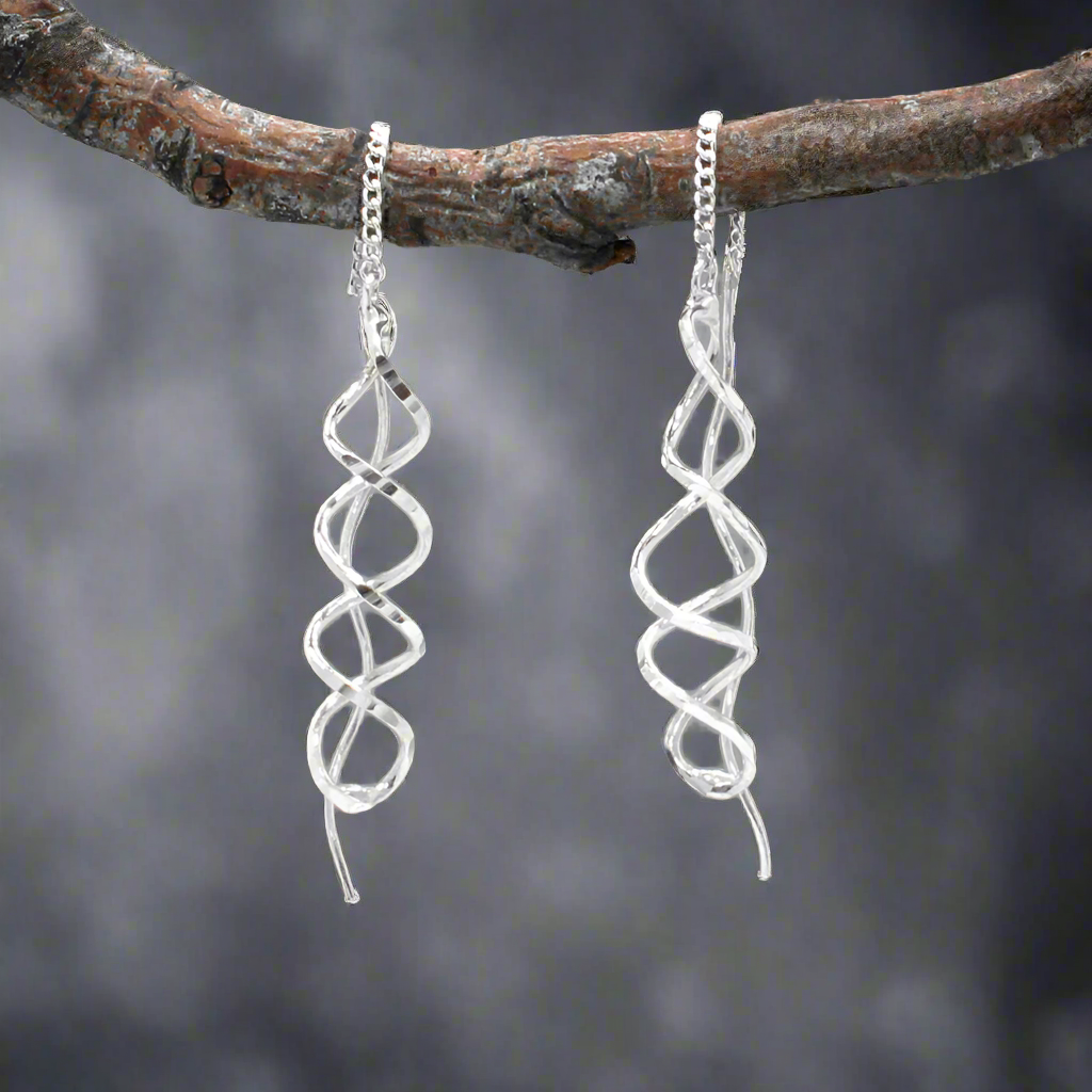 The Áine Small Helix Silver Threader Earrings bring a playful and elegant twist to your jewellery collection. These handcrafted earrings feature a slender helix shape with a lightly hammered finish, suspended from a fine silver chain that threads through the ear and connects to a polished post. The movement and shape give them a graceful, contemporary edge.