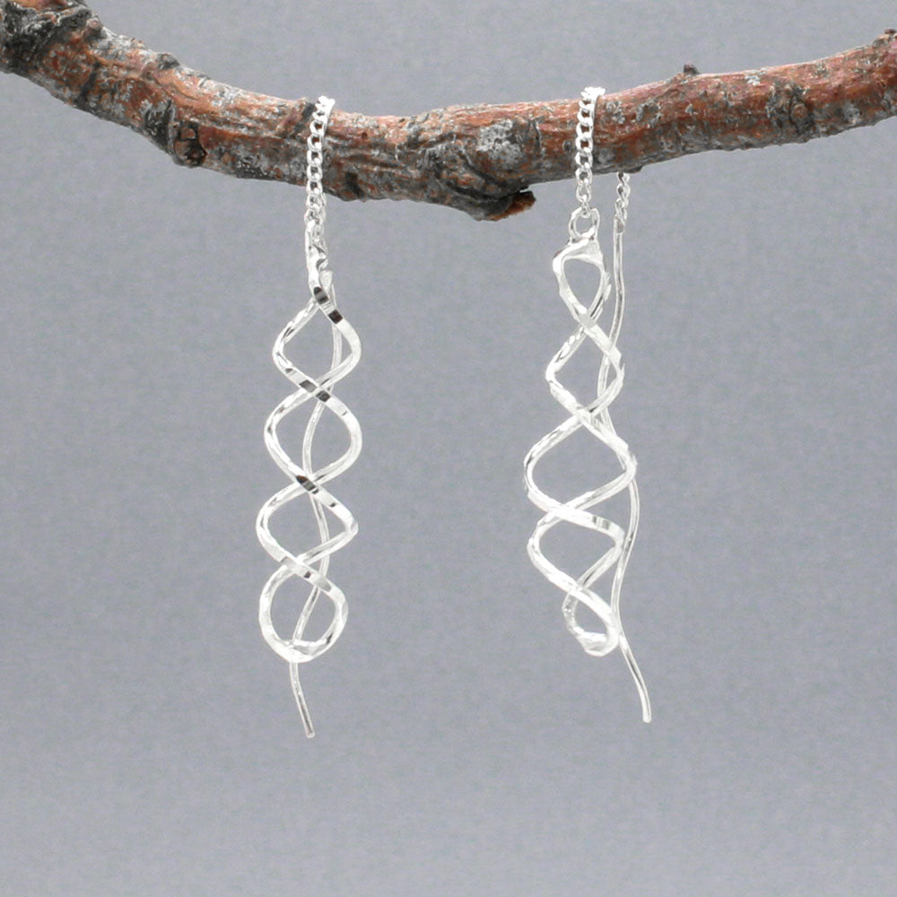 The Áine Small Helix Silver Threader Earrings bring a playful and elegant twist to your jewellery collection. These handcrafted earrings feature a slender helix shape with a lightly hammered finish, suspended from a fine silver chain that threads through the ear and connects to a polished post. The movement and shape give them a graceful, contemporary edge.