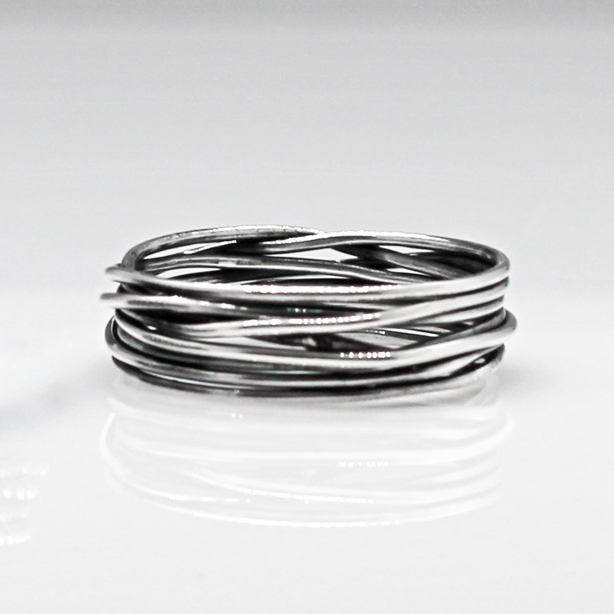 Aran - Lasso S Oxidised Silver Ring. Inspired by lasso rope designs, this piece offers a unique twist to your style. Crafted with oxidized sterling silver and featuring a comfortable 6mm band width, it's perfect for wearing solo or stacking with other rings to make a statement.