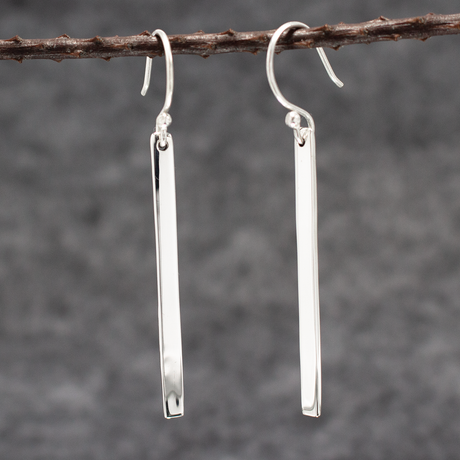 Artemis Slab Earrings: handcrafted elegance! Picture sterling silver gracefully dangling, adding timeless beauty to any look. These sleek earrings measure 40mm long by 3mm wide (approx. 1 & 5/8 inches long by 1/8 inches wide). Crafted from .950 sterling silver with a high-polished finish, they're wearable art. With secure dangle French wires, they offer comfort all day. 