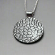 The Camila Disc Oxidised Silver Pendant features a bold, circular design with a striking cobblestone pattern. Crafted from .950 sterling silver, this pendant blends an oxidized texture with a highly polished silver finish.
Material: .950 sterling silver with an oxidized cobblestone pattern and highly polished finish
Dimensions:
Diameter: 30mm (1 3/16 inches)
Chain: Includes a 2.5mm sterling silver Rolo chain with a lobster claw clasp (select your preferred length)
Bail: Tube bail fits up to a 5mm chain (3/