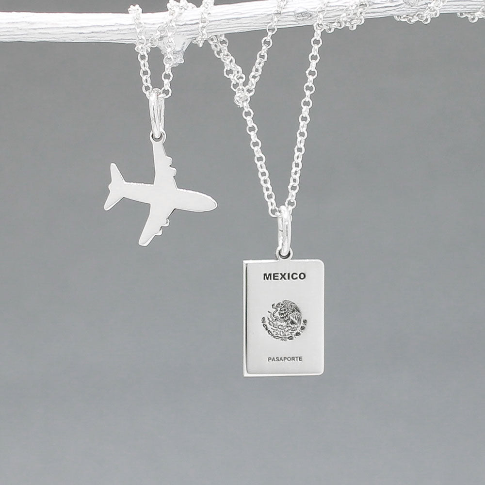 Our Mexican Passport Mini Replica Silver Pendant captures the intricate details of a Mexican passport cover, meticulously crafted from sterling silver with a high-polished finish. Dimensions: Passport: 10mm wide by 14mm high; Airplane: 14mm wide by 14mm high. Bail: Fits up to a 2.5mm chain for versatile wear. Chain: Includes a 1.4mm sterling silver belcher Rolo chain, available in various lengths.