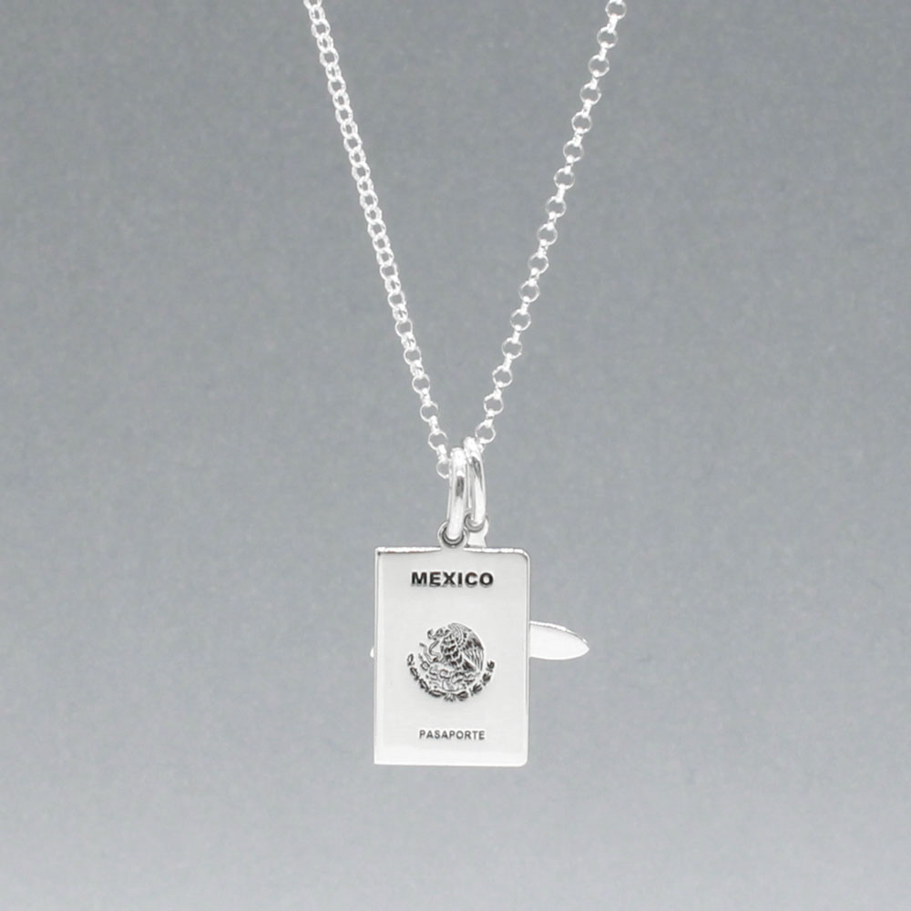Our Mexican Passport Mini Replica Silver Pendant captures the intricate details of a Mexican passport cover, meticulously crafted from sterling silver with a high-polished finish. Dimensions: Passport: 10mm wide by 14mm high; Airplane: 14mm wide by 14mm high. Bail: Fits up to a 2.5mm chain for versatile wear. Chain: Includes a 1.4mm sterling silver belcher Rolo chain, available in various lengths.
