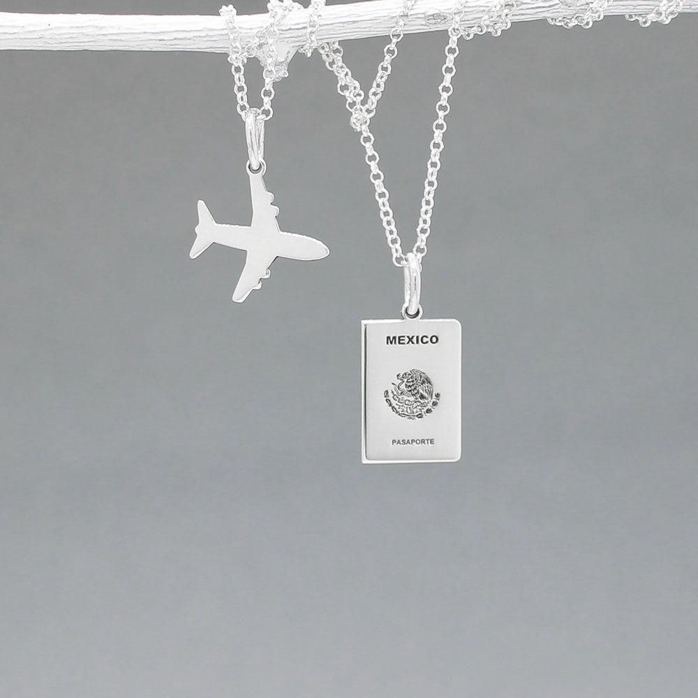 Our Mexican Passport Mini Replica Silver Pendant captures the intricate details of a Mexican passport cover, meticulously crafted from sterling silver with a high-polished finish. Dimensions: Passport: 10mm wide by 14mm high; Airplane: 14mm wide by 14mm high. Bail: Fits up to a 2.5mm chain for versatile wear. Chain: Includes a 1.4mm sterling silver belcher Rolo chain, available in various lengths.