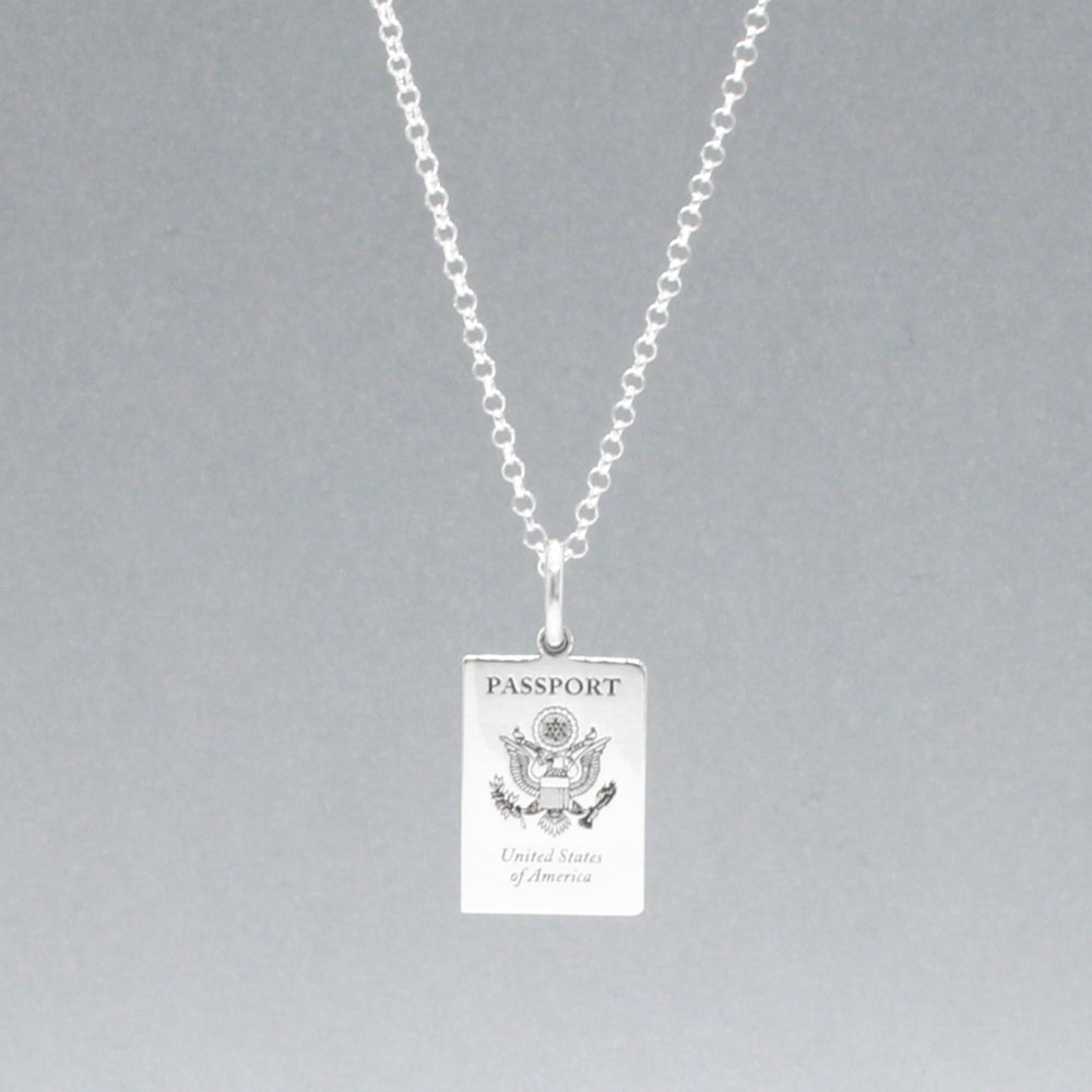 Our US Passport Mini Replica Silver Pendant captures the intricate details of a US passport cover, meticulously crafted from sterling silver with a high-polished finish. Dimensions: Passport: 10mm wide by 14mm high Airplane: 14mm wide by 14mm high Bail: Fits up to a 2.5mm chain for versatile wear. Chain: Includes a 1.4mm sterling silver belcher Rolo chain, available in various lengths.