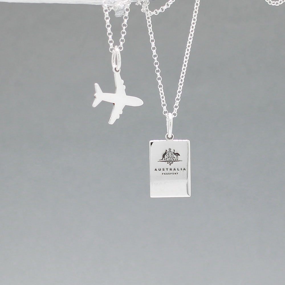 Our Australian Passport Mini Replica Silver Pendant captures all the intricate details of a passport cover. Meticulously crafted from sterling silver, it boasts a dazzling high-polished finish. Dimensions: Passport: 10mm wide by 14mm high Airplane: 14mm wide by 14mm high Bail: Fits up to a 2.5mm chain for versatile wear. Chain: Includes a 1.4mm sterling silver belcher Rolo chain, available in various lengths to suit your style preference.