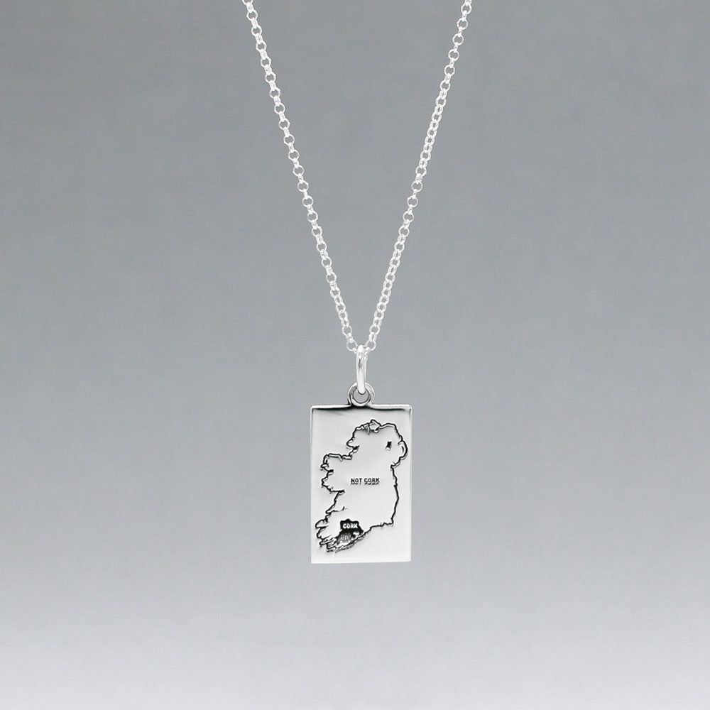Celebrate Cork with our Eire - Cork & Not Cork Silver Pendant.  Design: Features a map highlighting Co. Cork with a light oxidized finish, contrasting with the rest of Ireland. Dimensions: 13mm wide by 20mm long. Materials: Handmade from sterling silver. Chain: Includes a 1.4mm sterling silver Rolo chain with a spring clasp. Choose your preferred length during checkout.