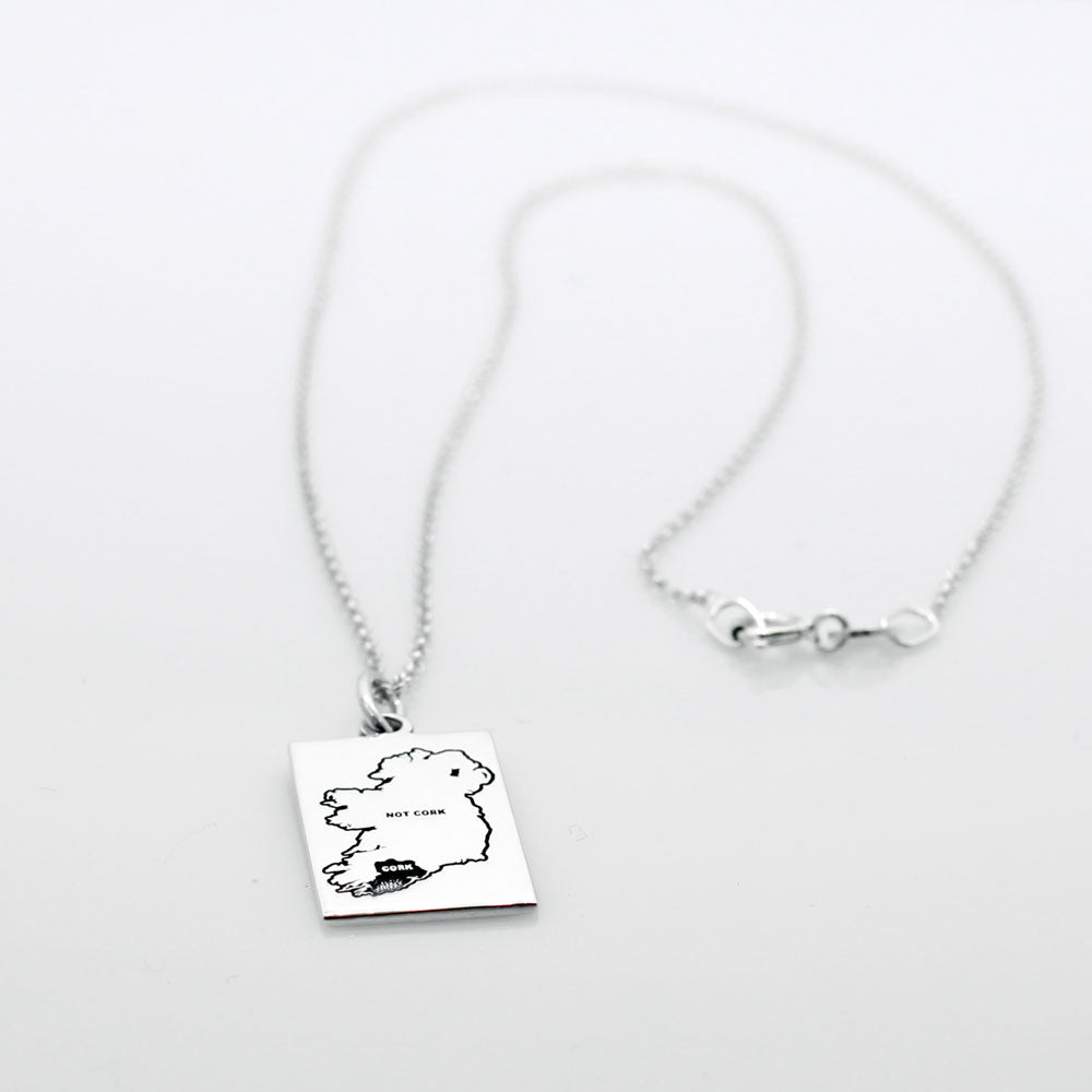 Celebrate Cork with our Eire - Cork & Not Cork Silver Pendant. Design: Features a map highlighting Co. Cork with a light oxidized finish, contrasting with the rest of Ireland. Dimensions: 13mm wide by 20mm long. Materials: Handmade from sterling silver. Chain: Includes a 1.4mm sterling silver Rolo chain with a spring clasp. Choose your preferred length during checkout.
