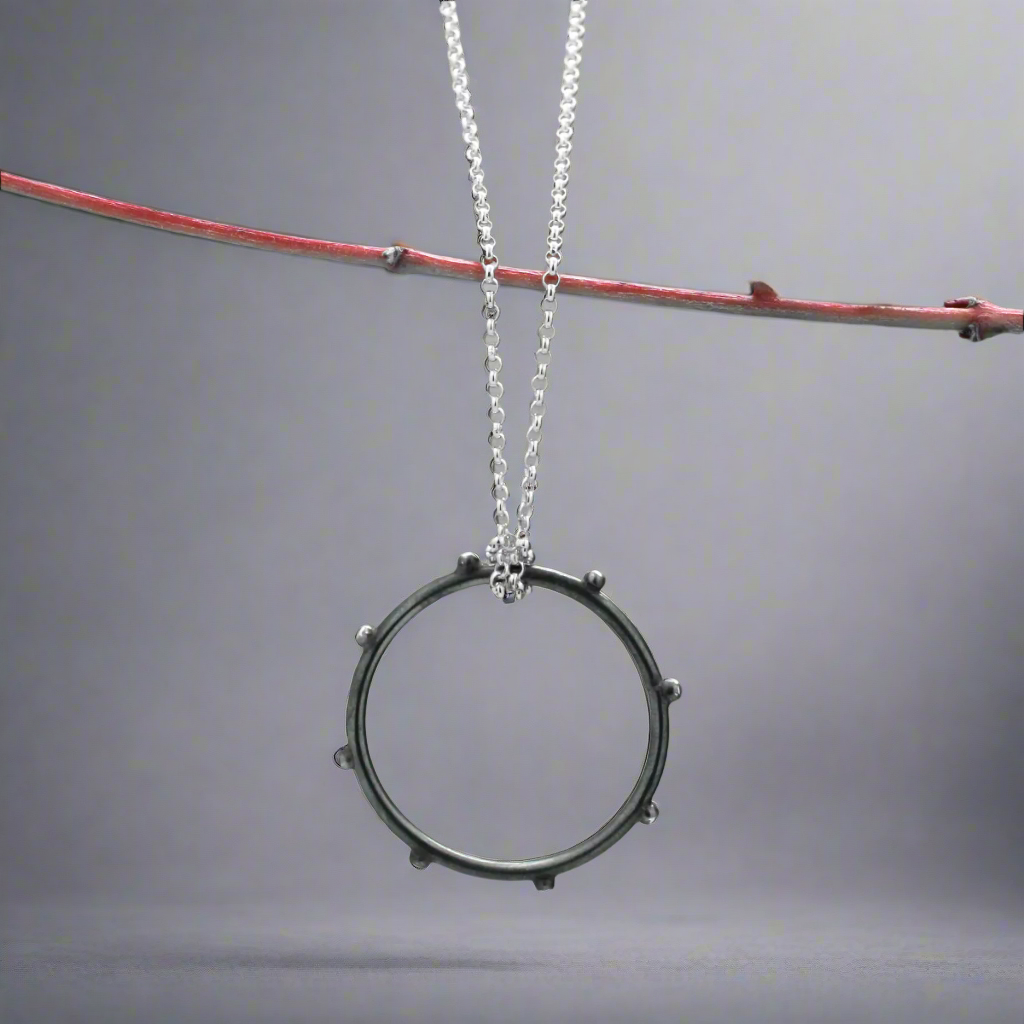 Make a statement with the Firmament - Aloe - Oxidised Circle with Dots Silver Pendant. This striking pendant, crafted from .925 sterling silver, features a unique dotted design in a circle shape with an oxidised and high-polished finish, adding depth and texture to the piece. A perfect gift or a treat for yourself, this pendant brings a touch of artistry to any look.