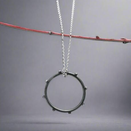 Make a statement with the Firmament - Aloe - Oxidised Circle with Dots Silver Pendant. This striking pendant, crafted from .925 sterling silver, features a unique dotted design in a circle shape with an oxidised and high-polished finish, adding depth and texture to the piece. A perfect gift or a treat for yourself, this pendant brings a touch of artistry to any look.