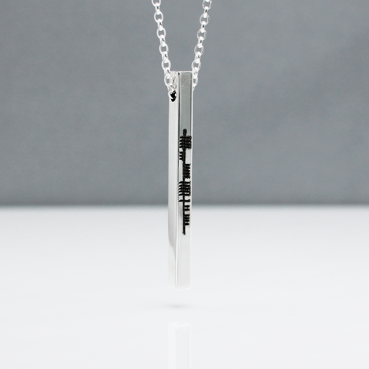 Our EIRE - Ogham Sláinte High Polished Bar Silver Pendant elegantly showcases intricate Ogham script spelling out the Irish word "Sláinte," a traditional toast meaning "health" in English. This word is often used when raising a glass in celebration or to wish good health to others.