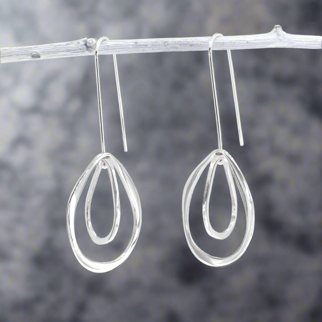 Add movement and elegance to your jewellery collection with the Saha Double Spinning Asymmetric Organic Oval Droplet Silver Earrings. These handcrafted sterling silver earrings feature a unique design of two spinning, asymmetric oval droplets, creating a dynamic and organic look. The high-polished finish enhances their modern charm, making them a versatile accessory for any occasion. Ireland jewellery