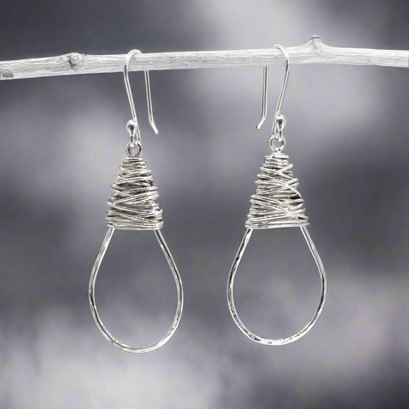 The Saha Drop Shape with Wire Wrap Silver Earrings bring timeless elegance to your jewellery collection. Handcrafted from sterling silver, these earrings feature a graceful drop shape accentuated with intricate wire wrapping. The highly polished finish adds a refined touch, making them ideal for both everyday wear and special occasions. Ireland jewellery
