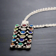 Sleveen Rectangle with Round Multi-Coloured Opalescence Mosaic Resin Silver Pendant. Sleveen's Rectangle with Round Multi-Coloured Opalescence Mosaic Resin Silver Pendant is a bold, statement piece that captures the vibrant charm of Kinsale. Featuring a blend of multi-coloured opalescent resin, this pendant reflects the lively, confetti-like hues of Kinsale’s iconic houses, adding a unique splash of colour to your collection.