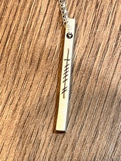 Discover the timeless elegance and captivating beauty of the EIRE - Ogham Grá & Wild Atlantic Way Matte Bar Silver Pendant. Boasting a 3.5mm width and 40mm length, it's laser engraved with Ogham Grá on one side and the Wild Atlantic Way symbol on the other. Show off your love for the Wild Atlantic Way with its adjustable silver rolo chain stretching from 18" to 20", offering virtually endless styling possibilities!