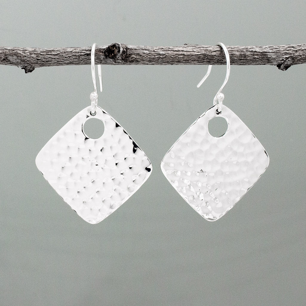 Nathalia - Rhombus Off-Center Dot Hammered Silver Earrings. With dimensions of 29mm long by 29mm wide, or roughly 1 1/4 inches square, they offer a bold yet elegant presence. The off-center dot design adds a unique flair to their hammered silver finish.