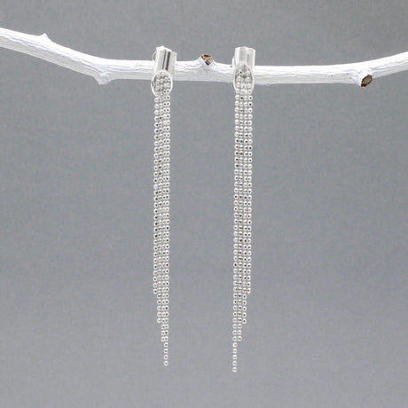 Áine - Cylinder with Chains Silver Earrings - Stud  Design: Four chains of different lengths cascading from the center of the cylinder Cylinder Diameter: 4 MM Total Length: 61 MM from top to bottom Material: Sterling silver with a highly polished finish Fastening: Sterling silver friction post