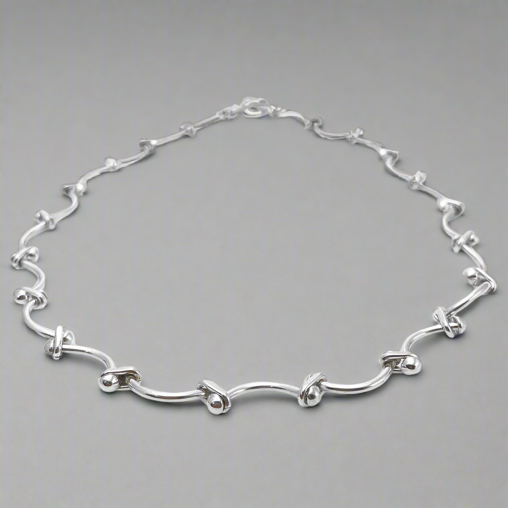 Áine Grace Silver Necklace is a perfect fusion of classic elegance and modern sophistication. Featuring delicately curved bar links accented with double 4 mm beads, this necklace is crafted in high-polished sterling silver to create a timeless, refined look. Ireland jewellry