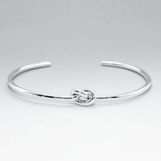 Aran - Single Knot Silver Cuff Bracelet  Material: Handmade sterling silver with a highly polished finish Dimensions: Thickness: 2.3 MM Knot: 7 MM wide, 11 MM long Inside Diameter: 55 MM x 43 MM Cuff Gap: 31 MM