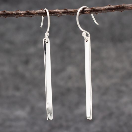 Artemis Slab Earrings: handcrafted elegance! Picture sterling silver gracefully dangling, adding timeless beauty to any look. These sleek earrings measure 40mm long by 3mm wide (approx. 1 &amp; 5/8 inches long by 1/8 inches wide). Crafted from .950 sterling silver with a high-polished finish, they're wearable art. With secure dangle French wires, they offer comfort all day.&nbsp;