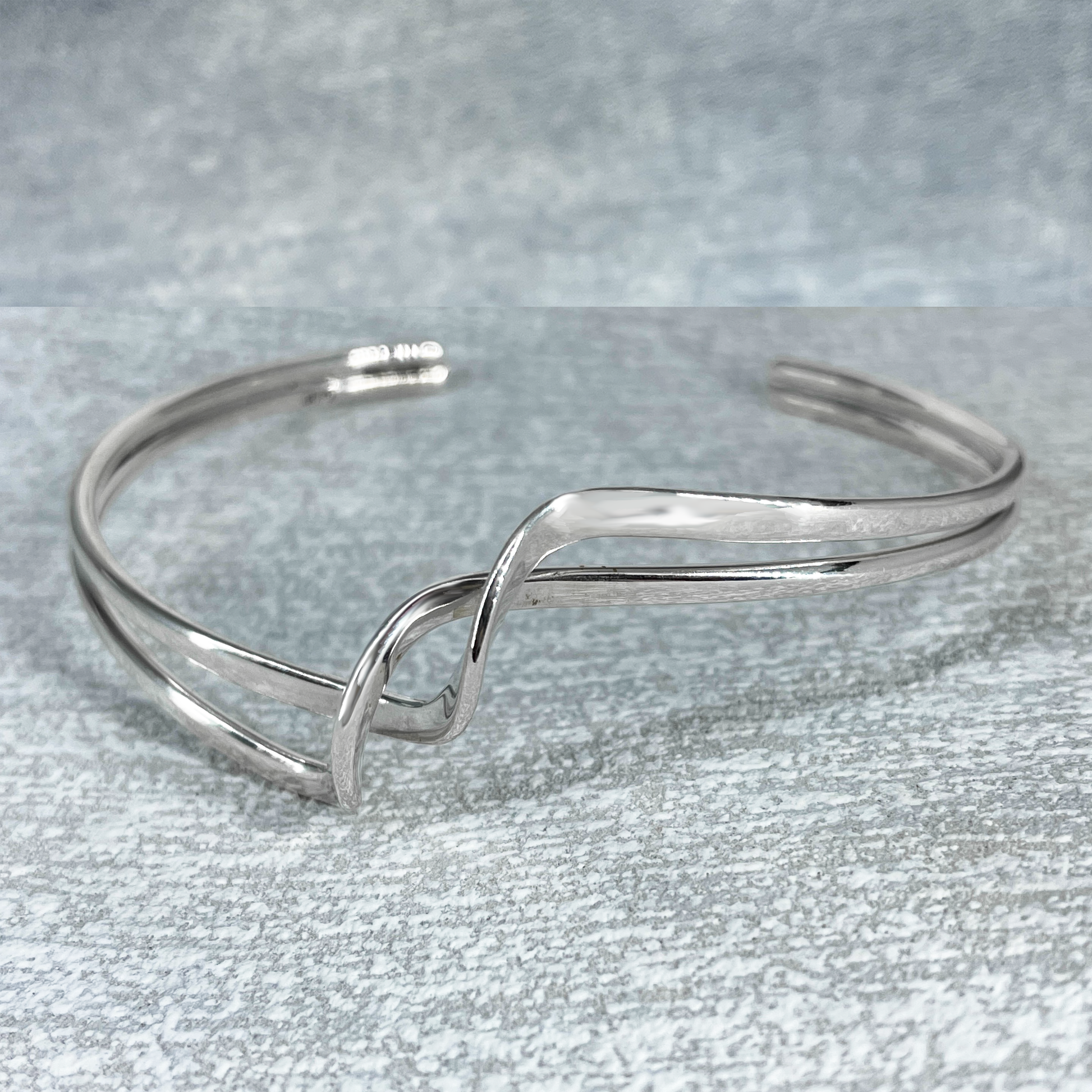 Uisce - Soft Double Wave with Crest Cuff Silver Bracelet, meticulously crafted from sterling silver and polished to perfection. This bracelet offers a thickness of 2 millimetres and can be effortlessly adjusted to ensure a perfect fit. Measuring 15 cm on the inner length and 16 cm on the outer length, with a width of 2 cm at its widest point and a 3 cm gap.