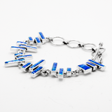 Sleveen's Blue Resin Opalescent Kinsale Steps Bracelet is a real showstopper! Crafted with a grand 18mm width, 3mm depth, and 19cm length, this bracelet features eye-catching blue opalescent resin steps. The toggle clasp is adjustable from 6" to 7.5" and made of .925 silver, making it a uniquely beautiful piece. Immerse yourself in the beauty of the stellar wild Atlantic with the mesmerizing blue hues of this bracelet!