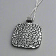 The Camila Square Oxidised Silver Pendant features a bold square design with a striking cobblestone pattern, blending oxidized and highly polished finishes. Crafted from .950 sterling silver, this pendant offers a unique texture that catches the eye.

Material: .950 sterling silver with oxidized and highly polished finishes, featuring a cobblestone pattern
Dimensions:
Size: 30mm long by 30mm wide (1 1/8 inches long by 1 1/8 inches wide)
Chain: Includes a 2.5mm sterling silver Rolo chain with a lobster claw 