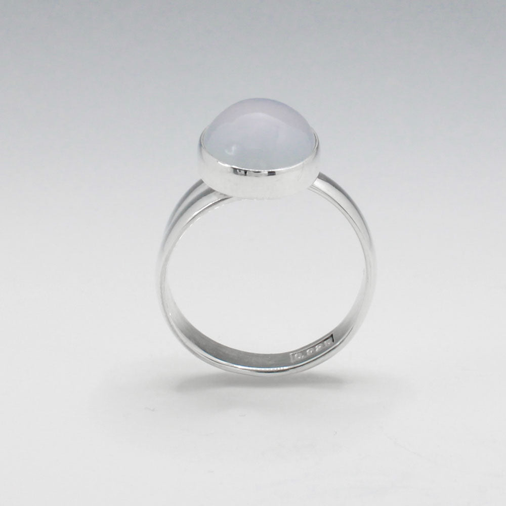 This exquisite ring features an oval blue chalcedony stone with a delicate light pink hue, set in high-quality sterling silver. The cabochon cut highlights the gemstone's natural beauty, while the adjustable band ensures a perfect fit for any wearer. This elegant piece adds a touch of sophistication and color to any outfit.