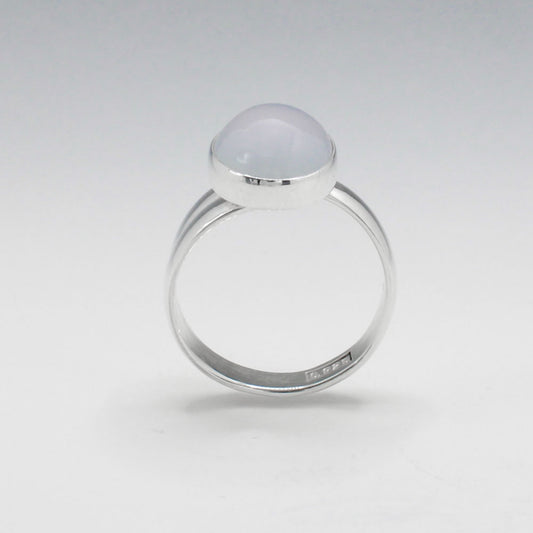 This exquisite ring features an oval blue chalcedony stone with a delicate light pink hue, set in high-quality sterling silver. The cabochon cut highlights the gemstone's natural beauty, while the adjustable band ensures a perfect fit for any wearer. This elegant piece adds a touch of sophistication and color to any outfit.