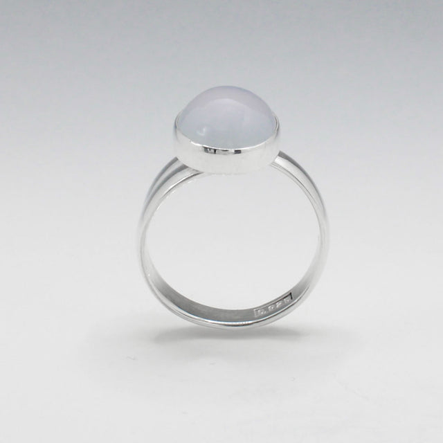 This exquisite ring features an oval blue chalcedony stone with a delicate light pink hue, set in high-quality sterling silver. The cabochon cut highlights the gemstone's natural beauty, while the adjustable band ensures a perfect fit for any wearer. This elegant piece adds a touch of sophistication and color to any outfit.