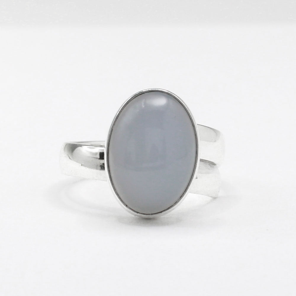 This exquisite ring features an oval blue chalcedony stone with a delicate light pink hue, set in high-quality sterling silver. The cabochon cut highlights the gemstone's natural beauty, while the adjustable band ensures a perfect fit for any wearer. This elegant piece adds a touch of sophistication and color to any outfit.