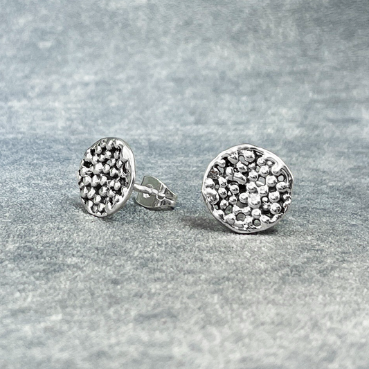 Uisce - Sea Foam Silver Earrings - Stud, meticulously handcrafted with sterling silver and boasting a high-polished finish. These earrings feature a unique texture resembling sea foam.  Expertly handmade with a thickness of 2 millimeters, they also feature sterling silver friction posts. Measuring 12 millimeters in diameter.