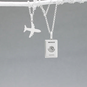Our Mexican Passport Mini Replica Silver Pendant captures the intricate details of a Mexican passport cover, meticulously crafted from sterling silver with a high-polished finish. Dimensions: Passport: 10mm wide by 14mm high; Airplane: 14mm wide by 14mm high. Bail: Fits up to a 2.5mm chain for versatile wear. Chain: Includes a 1.4mm sterling silver belcher Rolo chain, available in various lengths.