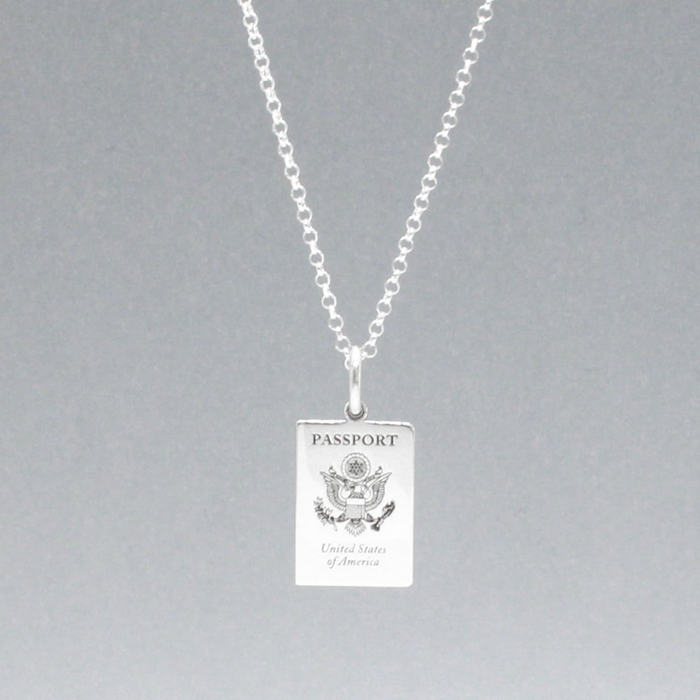 Our US Passport Mini Replica Silver Pendant captures the intricate details of a US passport cover, meticulously crafted from sterling silver with a high-polished finish.  Dimensions: Passport: 10mm wide by 14mm high Airplane: 14mm wide by 14mm high Bail: Fits up to a 2.5mm chain for versatile wear. Chain: Includes a 1.4mm sterling silver belcher Rolo chain, available in various lengths.