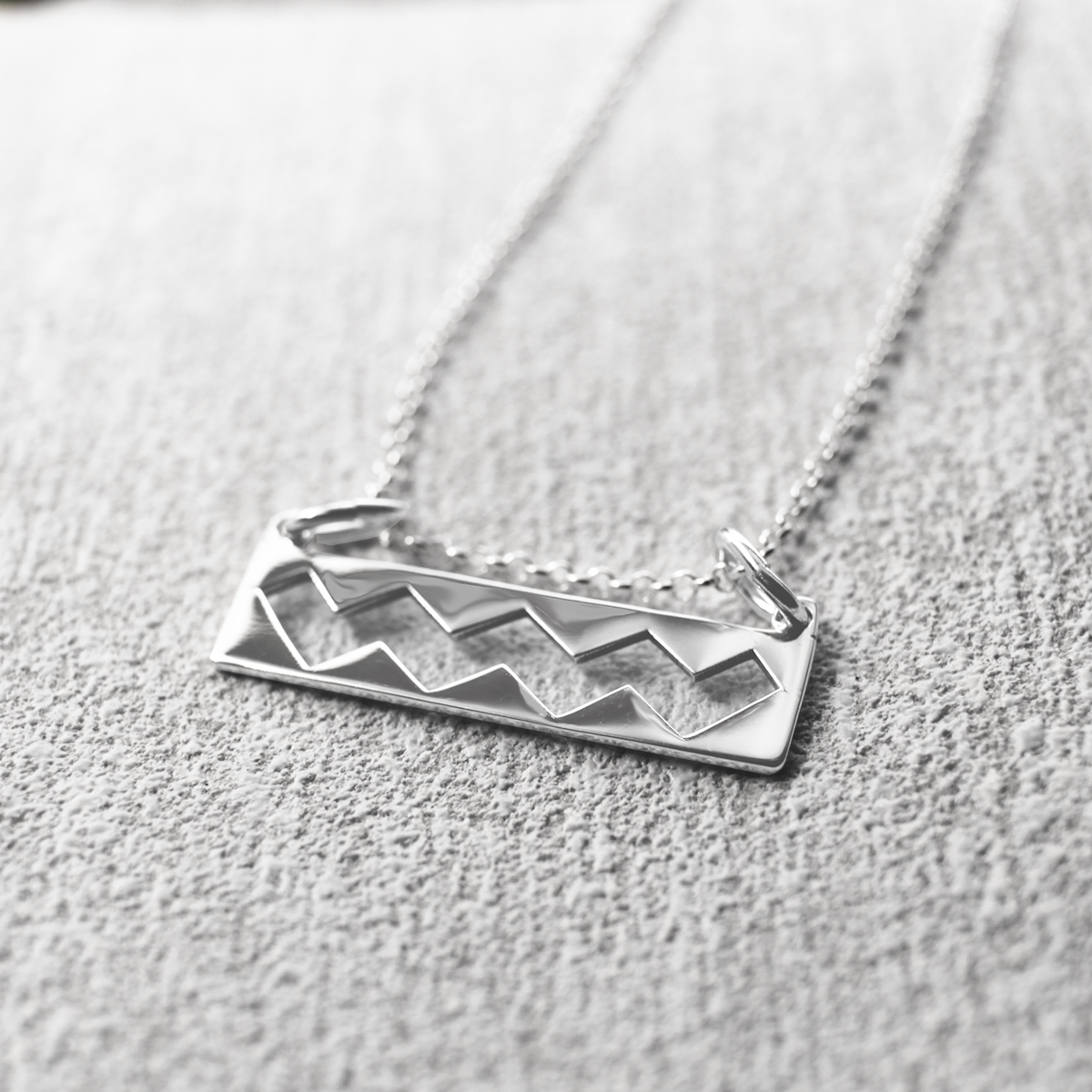 Experience the majestic beauty of Ireland with the EIRE - Wild Atlantic Way Silver Pendant. This stunning piece boasts dimensions of 25mm in width and 6mm in height, with a measurement of 12mm from the top of the bails. Its bail is designed to fit up to a 2.5mm chain. Included with the pendant is a 1.4 mm sterling silver belcher Rolo chain, available in various lengths to suit your style preference, whether you prefer it short or long. Irish gift
