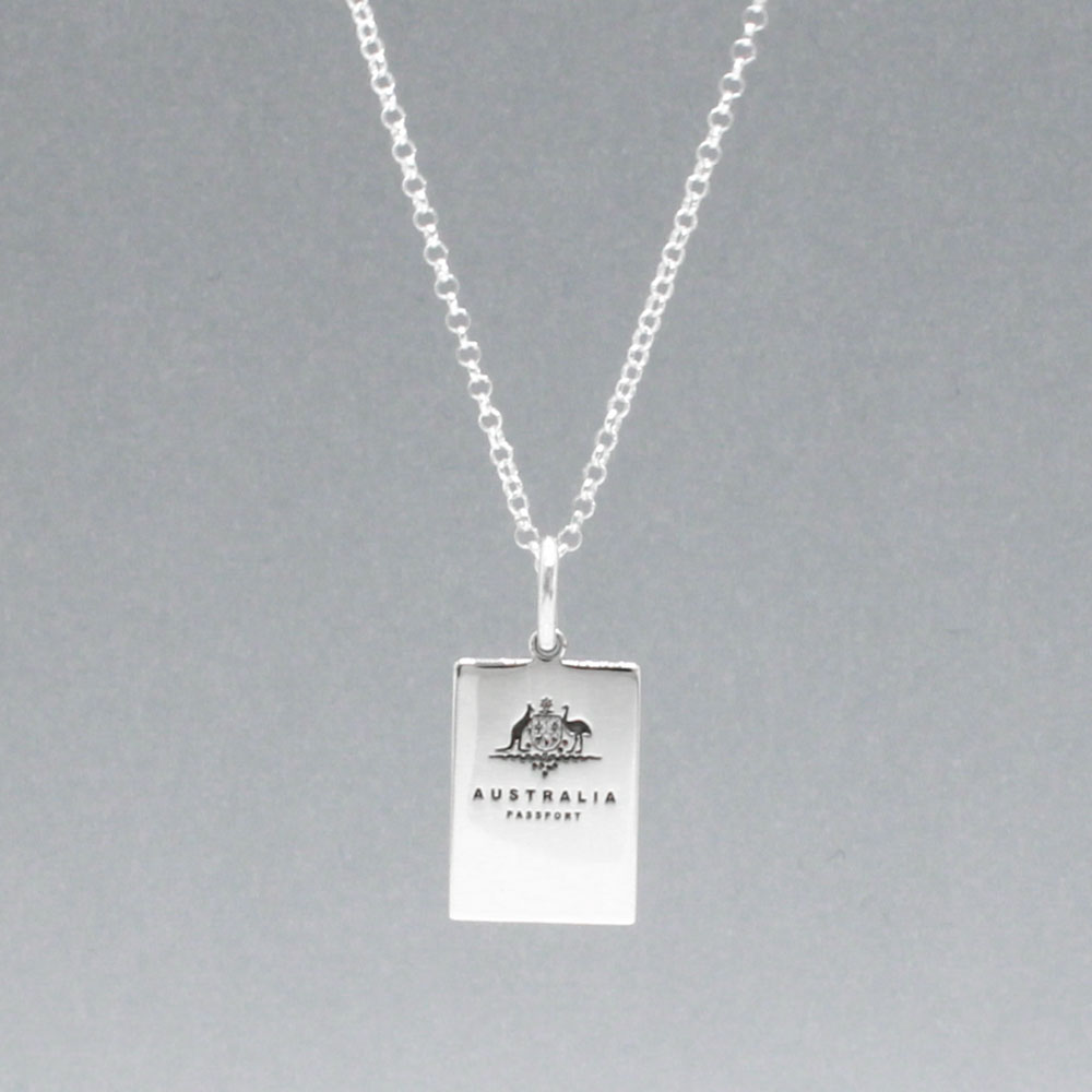 Our Australian Passport Mini Replica Silver Pendant captures all the intricate details of a passport cover. Meticulously crafted from sterling silver, it boasts a dazzling high-polished finish.  Dimensions: Passport: 10mm wide by 14mm high Airplane: 14mm wide by 14mm high Bail: Fits up to a 2.5mm chain for versatile wear. Chain: Includes a 1.4mm sterling silver belcher Rolo chain, available in various lengths to suit your style preference.