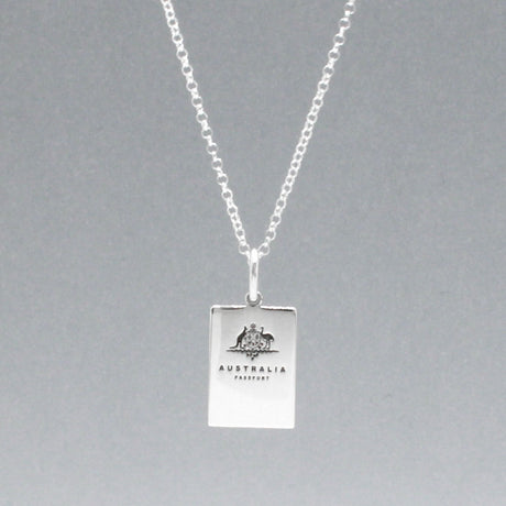 Our Australian Passport Mini Replica Silver Pendant captures all the intricate details of a passport cover. Meticulously crafted from sterling silver, it boasts a dazzling high-polished finish.  Dimensions: Passport: 10mm wide by 14mm high Airplane: 14mm wide by 14mm high Bail: Fits up to a 2.5mm chain for versatile wear. Chain: Includes a 1.4mm sterling silver belcher Rolo chain, available in various lengths to suit your style preference.