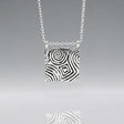 Inspired by the Newgrange Stone Dimensions: 20mm wide x 24mm high (including bail), 2mm thick Finish: Oxidized to accentuate the design, with a high polished finish Material: Handmade with 0.50 sterling silver Chain: 1.7mm sterling silver rolo chain included (select chain size below) Celebrate the ancient beauty of Newgrange with our Cropped Square Silver Pendant. This unique piece is expertly crafted to honor Ireland's rich heritage.