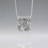 Inspired by the Newgrange Stone Dimensions: 20mm wide x 24mm high (including bail), 2mm thick Finish: Oxidized to accentuate the design, with a high polished finish Material: Handmade with 0.50 sterling silver Chain: 1.7mm sterling silver rolo chain included (select chain size below) Celebrate the ancient beauty of Newgrange with our Cropped Square Silver Pendant. This unique piece is expertly crafted to honor Ireland's rich heritage.
