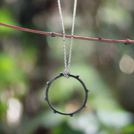 Make a statement with the&nbsp;Firmament - Aloe - Oxidised Circle with Dots Silver Pendant. This striking pendant, crafted from .925 sterling silver, features a unique dotted design in a circle shape with an oxidised and high-polished finish, adding depth and texture to the piece. A perfect gift or a treat for yourself, this pendant brings a touch of artistry to any look.