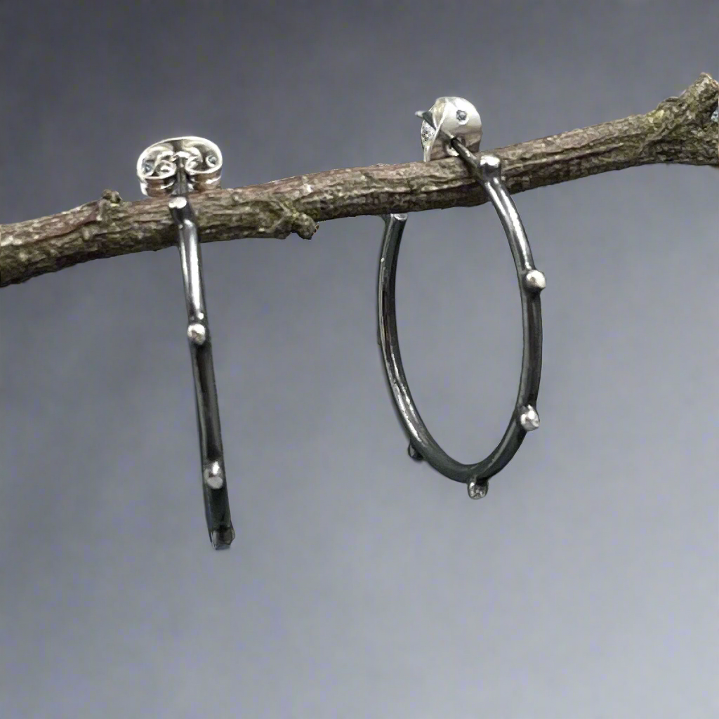 Add a unique touch to your collection with the Firmament - Aloe Oxidised Hoop Silver Earrings. Crafted from high-quality .925 sterling silver, these earrings feature a stylish dot design that catches the eye. Croí Kinsale Jewellery, located in the heart of Kinsale, to explore this stunning piece and more!