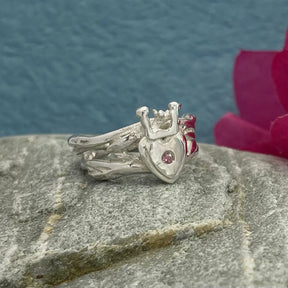 Double Claddagh Silver Ring with a Touch of Pink Tourmaline Design: Organic Claddagh inspired by twigs and Irish coral Material: Solid sterling silver cast Finish: Highly polished Band: 7.5mm in width Centre: Heart and crown measure 13mm long Accent: 1mm pink tourmaline A beautifully crafted piece that blends tradition with nature’s elegance. Perfect for expressing love, loyalty, and friendship.