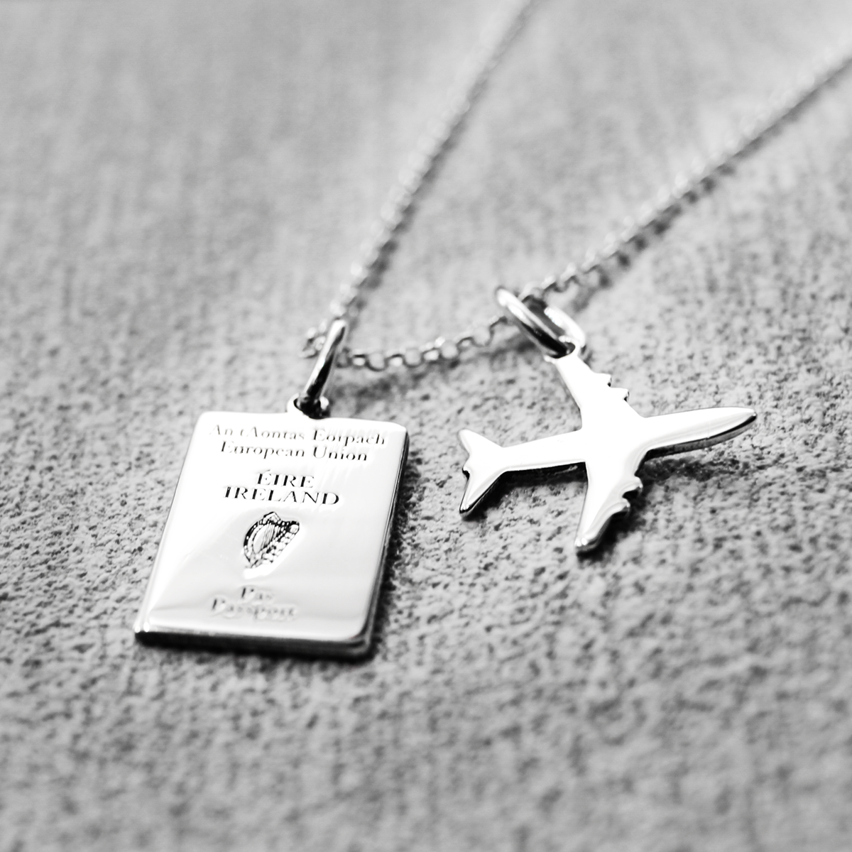 Irish Passport Replica Mini Silver Pendant with Mini Airplane Charm Pendant by Croí Kinsale Jewellery.  The passport measures 10 millimeters wide by 14 millimeters high, while the airplane charm measures 14 millimeters wide by 14 millimeters high. The bail fits up to a 2.5 mm chain, offering versatility for different chain sizes. Whether you gift it to a wanderer or keep it as a timeless heirloom, this pendant is a symbol of Irish pride and wanderlust. Irish souvenir