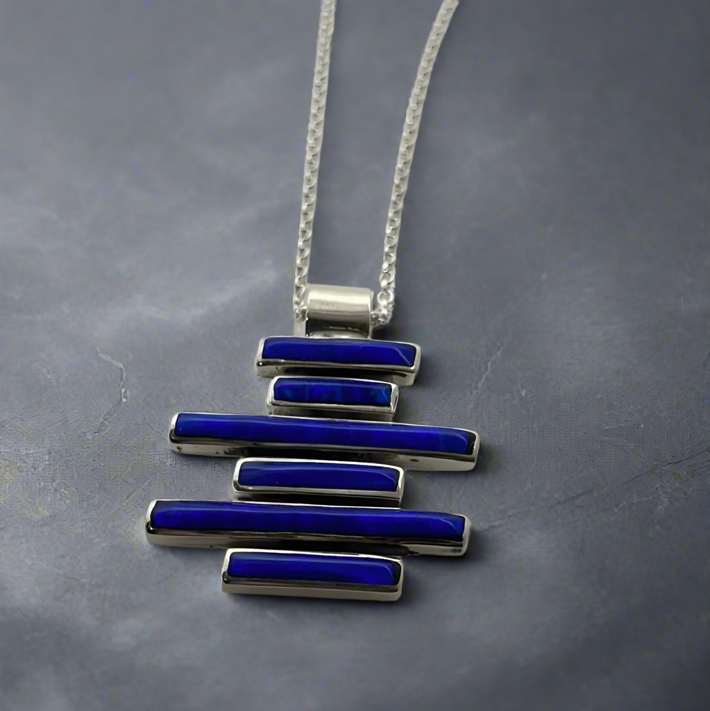 Sleveen Dark Blue Opalescent Kinsale Steps Silver Pendant. Add a vibrant splash of Kinsale’s iconic charm to your look with the&nbsp;Sleveen - Kinsale Steps - Dark Blue Opalescent Resin Silver Pendant. Inspired by the seaside beauty of Kinsale, this stunning pendant is handcrafted from .925 sterling silverand features a striking dark blue opalescent resin. It’s the perfect piece to bring a joyful touch to your style.