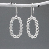 These handmade, sterling silver dangle earrings are a perfect blend of elegance and modern design. Features:  Oblong measures 17mm wide by 27mm high 4mm thick 40mm long from the top of the ear wire Made from sterling silver Handcrafted Highly polished finish for a brilliant shine Ideal for any occasion, these earrings add a touch of sophistication to any outfit.