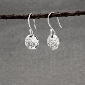 These Artemis earrings are crafted from .950 sterling silver and feature a beautiful hammered finish, adding unique texture. Material: .950 sterling silver Dimensions: Disc Diameter: 10 mm (approx. 3/8 inches) Total Length (from top of ear wire): 22 mm (approx. 7/8 inches) Design: Dangle earrings with a hammered finish Closure: Sterling silver French wire These earrings are perfect for any outfit.