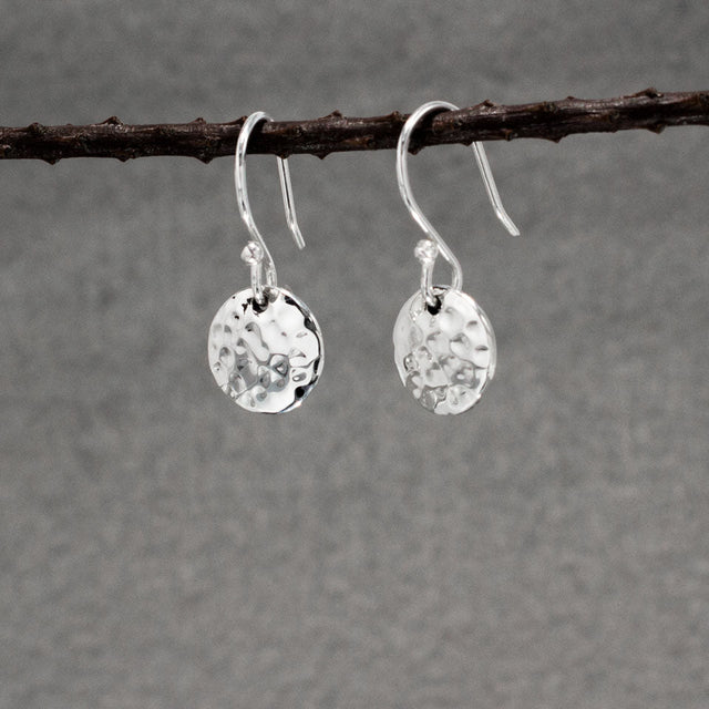 These Artemis earrings are crafted from .950 sterling silver and feature a beautiful hammered finish, adding unique texture.  Material: .950 sterling silver Dimensions: Disc Diameter: 10 mm (approx. 3/8 inches) Total Length (from top of ear wire): 22 mm (approx. 7/8 inches) Design: Dangle earrings with a hammered finish Closure: Sterling silver French wire These earrings are perfect for any outfit.